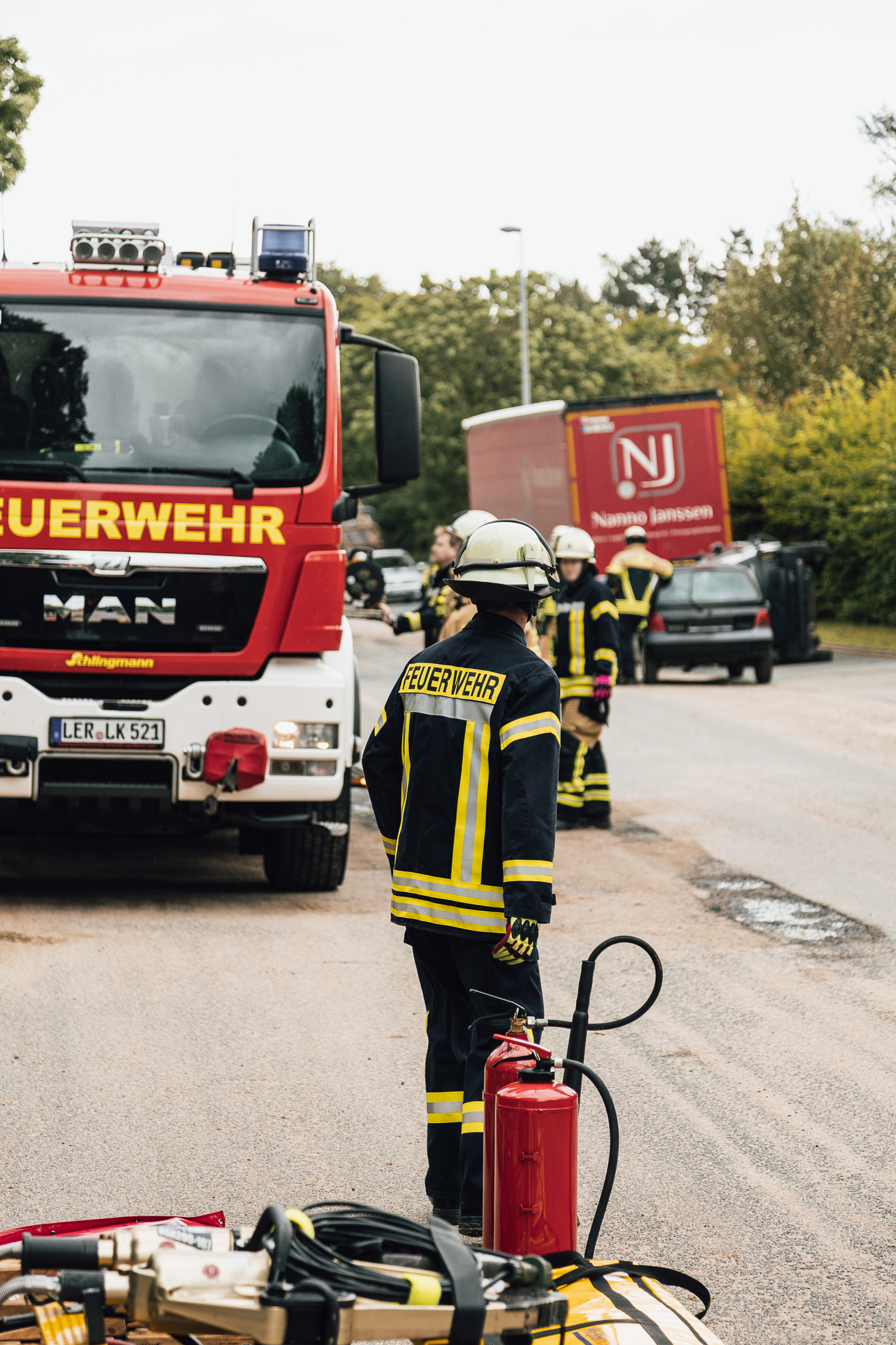 Feuerwehr-Mitglieder bei einer Übung, im Hintergrund ein großes Löschfahrzeug